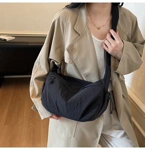 Dettaglio della borsa a mezzaluna in nylon nero con tracolla larga e coulisse laterale