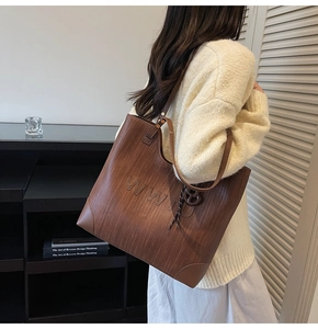 Detail of a brown tote bag with woven texture and WW letter logo on a model
