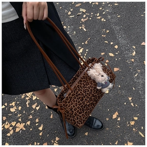 Detalle de bolso tote con estampado de leopardo, colgante de oso y correa marrón