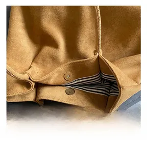 Detail of matte brown suede tote featuring gold magnetic snaps and striped fabric lining