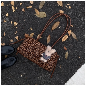 Detalle del bolso de hombro con estampado de leopardo y colgante de oso en otoño