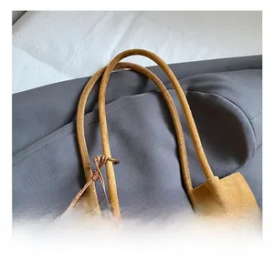 Detail of ginger yellow matte suede tote bag with GOTH logo and wooden bead tassel