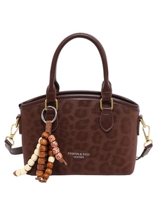 Leopard print suede bucket bag with wooden bead charm and dual handles on white background