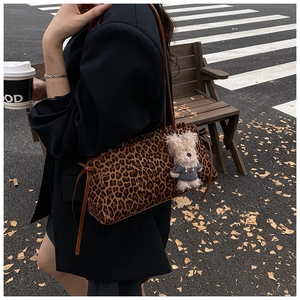 Bolso de hombro de leopardo con colgante de osito de peluche en una escena callejera otoñal
