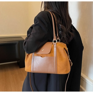 Detailansicht einer großen Wildleder-Tragetasche in Camel mit braunem Leder und Goldbeschlägen