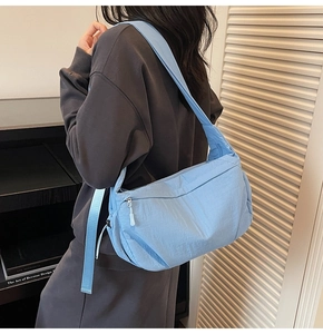 Dettaglio della borsa a mezzaluna in nylon azzurro con tracolla larga e cerniera bianca