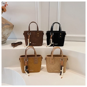 Détail de sacs seaux en daim matelassé avec glands en perles de bois et finitions dorées