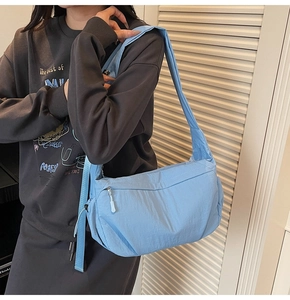 Dettaglio della borsa a tracolla azzurra in nylon stile dumpling indossata da una modella