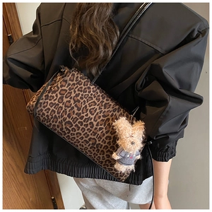 Detalle del bolso tote con estampado de leopardo y tierno colgante de oso en la correa negra