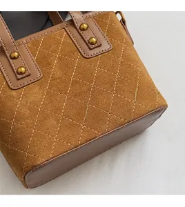 Détail d'un sac seau matelassé marron avec rivets dorés et texture en cuir