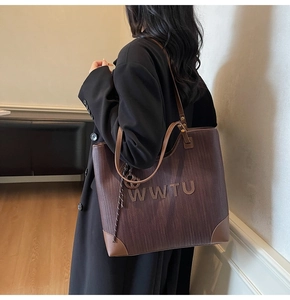 Detail of large brown woven tote bag with leather straps on a female model side view