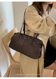 Detail of deep brown matte leather tote bag with side drawstring knot and logo