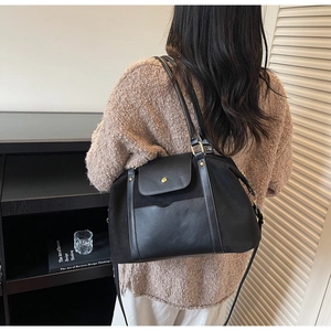 Detailaufnahme der schwarzen matten Ledertasche mit goldenen Beschlägen und Seitentasche