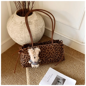 Detalle del bolso boston de leopardo con colgante de conejo y lazos decorativos laterales