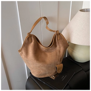 Detailed close-up of brown suede hobo bag with smooth leather trim in an indoor setting