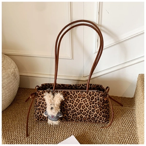 Detalle del bolso de leopardo con asas marrones y un colgante de conejo de peluche