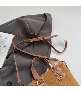 Détail d'un sac seau en daim matelassé marron avec finitions en cuir et rivets dorés