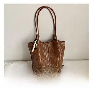 Detailed cross-weave texture and vintage beaded charm on brown woven tote bag