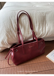 Detail of burgundy tote bag with litchi grain texture and adjustable shoulder strap