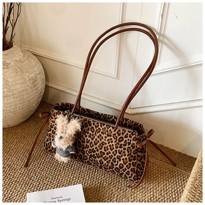 Detalle del bolso de leopardo con correas de cuero marrón y colgante de oso de peluche