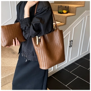 Detailed close-up of woven leather texture on a brown tote bag and matching pouch