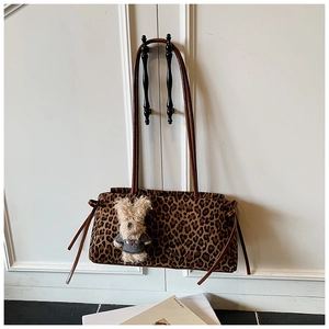 Detalle de bolso con estampado de leopardo, correas de cuero marrón y colgante de conejo