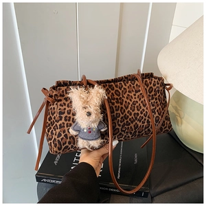 Detalle del bolso tote de leopardo con cordón marrón y colgante de osito de peluche