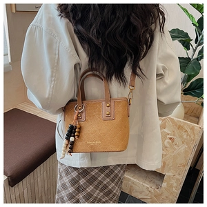 Détail du sac seau en daim rétro avec motifs matelassés et perles en bois colorées