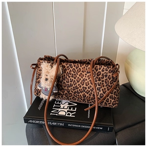 Detalle de bolso de hombro con estampado de leopardo, correas de cuero y osito de peluche
