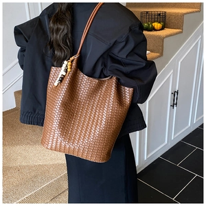 Brown woven leather tote bag with stylish beaded pendant shown in a lifestyle scene
