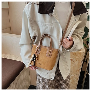 Détail du sac seau en daim marron vintage avec matelassage en losange et breloque en perles
