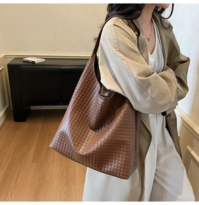 Detailed view of brown woven leather texture on a spacious commuter shoulder bag