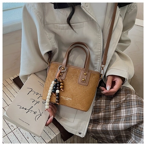 Gros plan sur un sac seau marron en daim avec surpiqûres et pendentif à perles