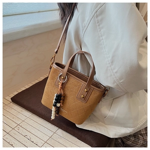 Détail du sac seau en daim vintage avec motif en losanges et pompon en perles