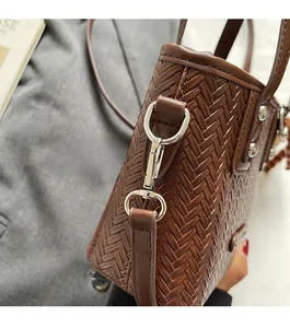 Gros plan du sac seau marron tressé avec fermoir mousqueton argenté et détails en métal