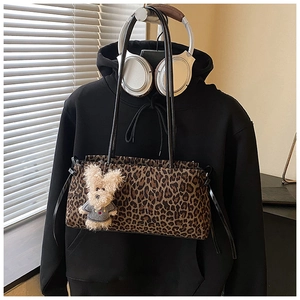 Detalle de bolso de hombro con estampado de leopardo, correas negras y colgante de oso