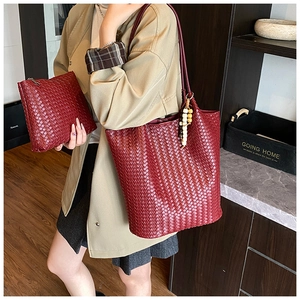Detail of burgundy woven tote bag and matching small pouch set with leather texture
