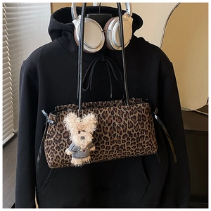 Detalle del bolso de leopardo con colgante de perro de peluche y lazos en los laterales