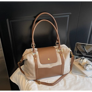 Detail der großen Tasche aus beigem Canvas und braunem Leder mit goldenen Beschlägen