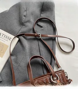 Détail du tissage en cuir marron et de la bandoulière réglable sur le sac seau