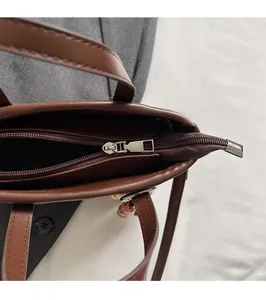 Détail de la fermeture éclair argentée sur le sac seau marron à texture tressée