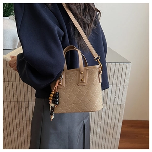 Détail d'un sac seau vintage en daim avec surpiqûres et gland en perles de bois
