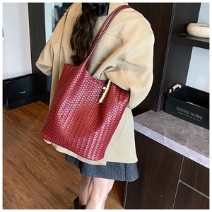 Detail of dark red woven tote bag featuring decorative wooden beads and slim straps
