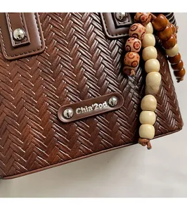 Détail de la texture en cuir tressé marron foncé avec plaque métallique argentée