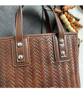 Détail du sac seau en cuir tressé marron avec rivets renforcés et pendentif en perles de bois