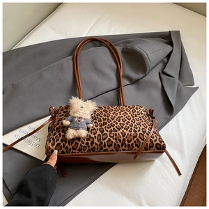 Detalle de bolso tote de leopardo con base de cuero marrón y adorno de osito de peluche