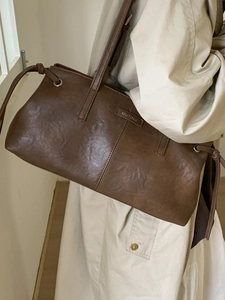 Dark brown retro leather tote bag worn by model with beige trench coat for office commute