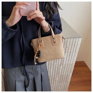 Détail du sac seau en daim kaki avec motifs matelassés et rivets dorés élégants
