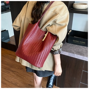 Detail of burgundy woven leather tote bag with decorative beads and large weave texture