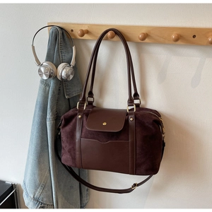 Makroaufnahme einer tiefbraunen Boston-Tasche aus Wildleder und Leder an einem Wandhaken